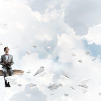 Funny man in red glasses and suit sitting on book and paper planes flying around